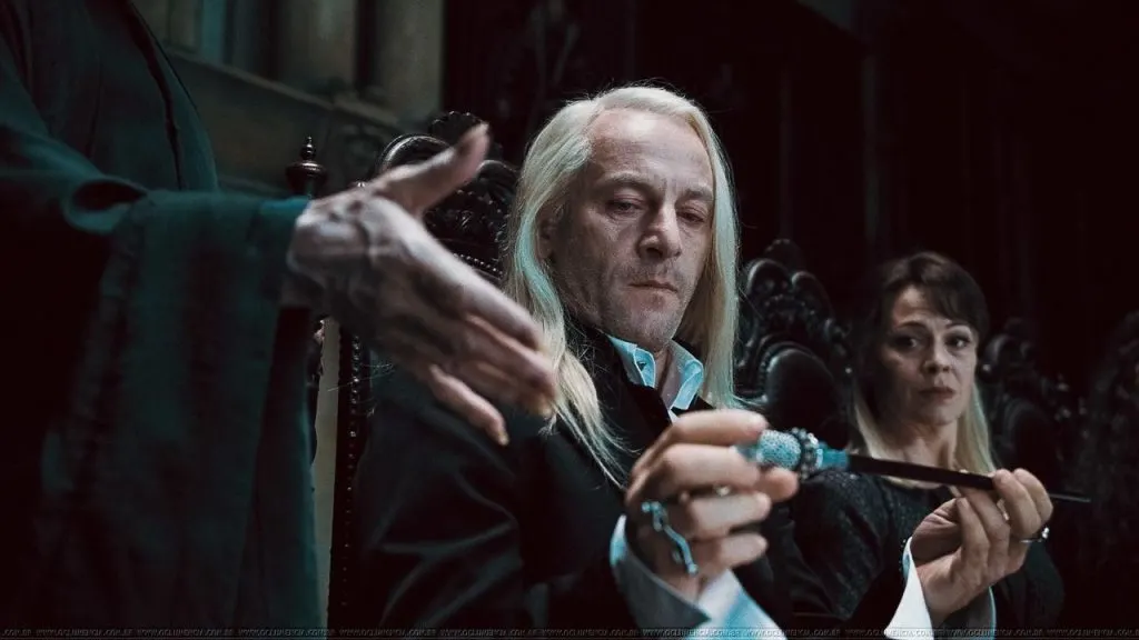 Lucius Malfoy gives Lord Voldemort his wand